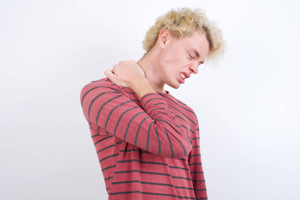young blond man Suffering of neck ache injury, touching neck with hand, muscular pain - Photo, Image