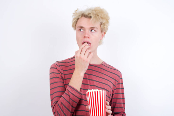 Nuori mies popcornia valkoisella taustalla - Valokuva, kuva