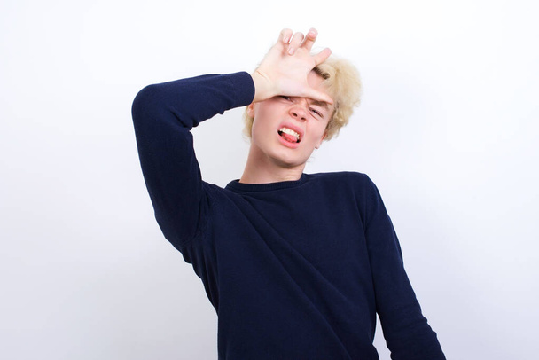 young caucasian man making fun of people with fingers on forehead doing loser gesture mocking and insulting. - Photo, Image