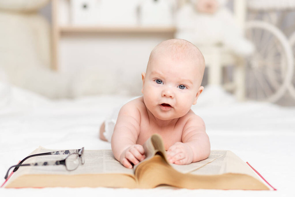 baby reading a book or looking at it in the nursery, learning and development concept - Φωτογραφία, εικόνα