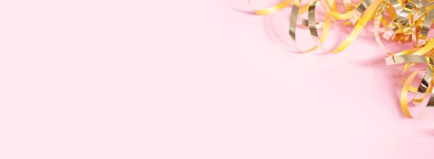 Блестящие золотые змеиные ленты на розовом фоне. Знамя с копировальным пространством. Вид сверху, плоский - Фото, изображение