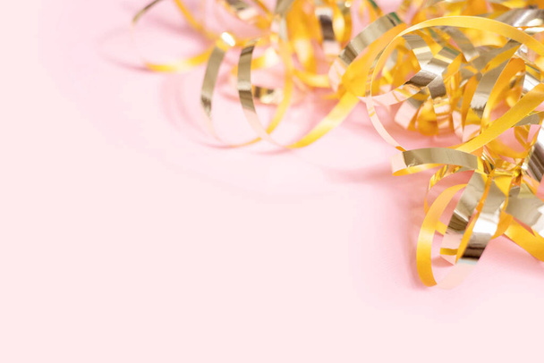Serpentins dorés brillants sur fond rose avec espace de copie. Vue de dessus, plan plat - Photo, image