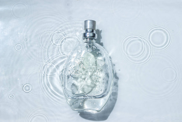 Perfume bottle on the surface of the water. Circle ripples on water surface. Pure clear water - Foto, imagen