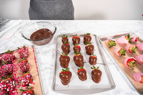 Zubereitung von mit Schokolade überzogenen Erdbeeren auf einem Plätzchenblech. - Foto, Bild