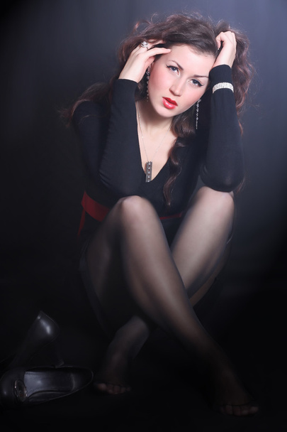 Красива дівчина в чорній сукні, що сидить на підлозі
 - Фото, зображення