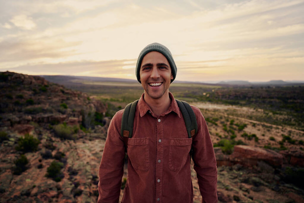 Portrait of successful happy male hiker with backpack and cap looking at camera - 写真・画像
