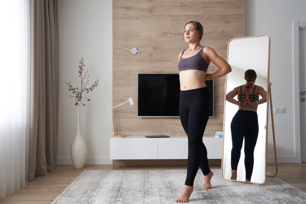 Junge Frau in Sportkleidung macht Yoga und entspannt sich zu Hause - Foto, Bild