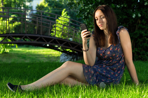 Hermosa chica con teléfono en el parque
 - Foto, imagen