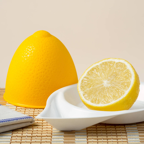 Half fresh lemon in a lemon plastic bowl on bamboo napkin - Foto, Imagen