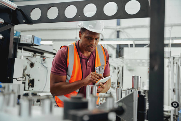 Industrial technician wearing hardhat examining stock in industry using digital tablet - Foto, Bild