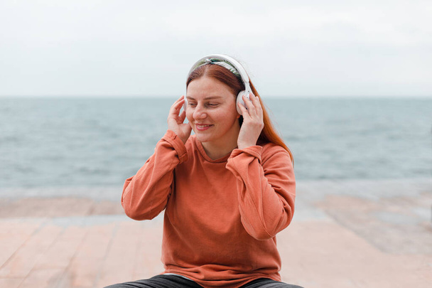 Közelkép portré fiatal mosoly lány meditál vezeték nélküli fejhallgató a strandon - Fotó, kép