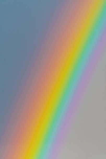 Closeup of intense and vibrant rainbow in gray sky. Meteorology, weather and symbolism concepts - 写真・画像