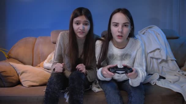Dos amigos emocionados vitoreando después de ganar en el videojuego en la consola por la noche - Imágenes, Vídeo