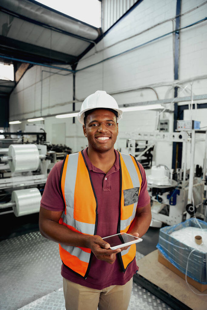 Young industrialist in work wears standing with digital tablet in factory warehouse - Foto, Imagem