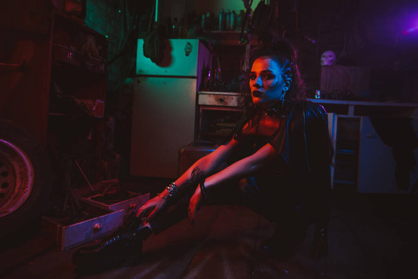 Cyberpunk girl in a steampunk costume in a garage with neon lighting - Foto, afbeelding