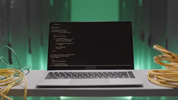 黒の画面上で実行されているコンピュータコードのプログラムとポータブルコンピュータのSteadicamは、緑の照明の部屋の表面に立って - 映像、動画