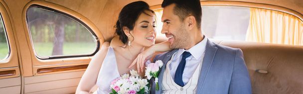 Cheerful bride with bouquet looking at groom in vintage auto, banner  - Foto, Imagem