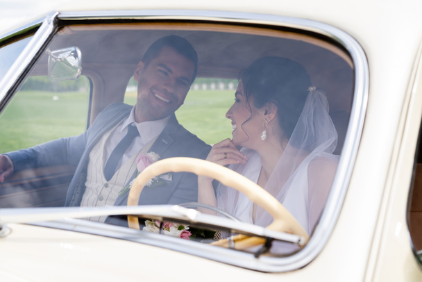 Vidám menyasszony és vőlegény nézik egymást retró autóban.  - Fotó, kép
