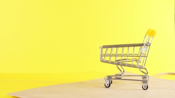 άδειο καλάθι αγορών σε κίτρινο φόντο, κοντινό πλάνο. Μαύρη Παρασκευή Αγορές και έκπτωση Concept - Πλάνα, βίντεο