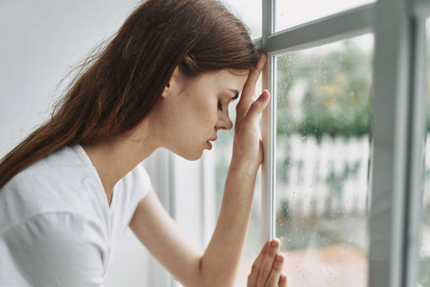 грустная женщина, прислонившаяся к стеклянному окну и печальной комнате модели лица - Фото, изображение
