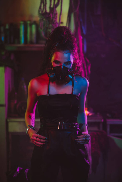 девушка в стиле киберпанк в костюме противогаза с неоновым светом ночью - Фото, изображение