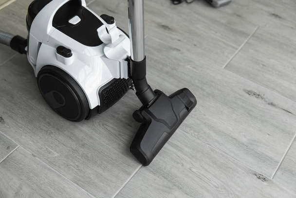 Bagless cyclone vacuum cleaner on a grey tile. Electrical apparatus that by means of suction collects dust and small particles from floors and other surfaces. - Zdjęcie, obraz