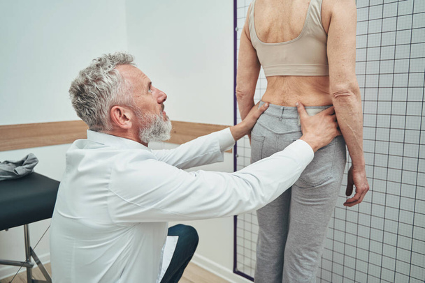 Physiotherapeut untersucht Lendenwirbelsäule einer Patientin - Foto, Bild
