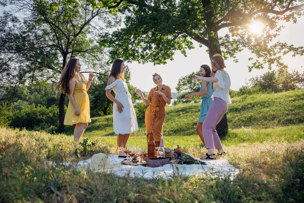 Summer party, Outdoor Gathering with friends. Five young women, Friends at the picnic dancing and having fun on summer vacation. Group of female friends enjoying at outdoors party on nature. - Foto, immagini