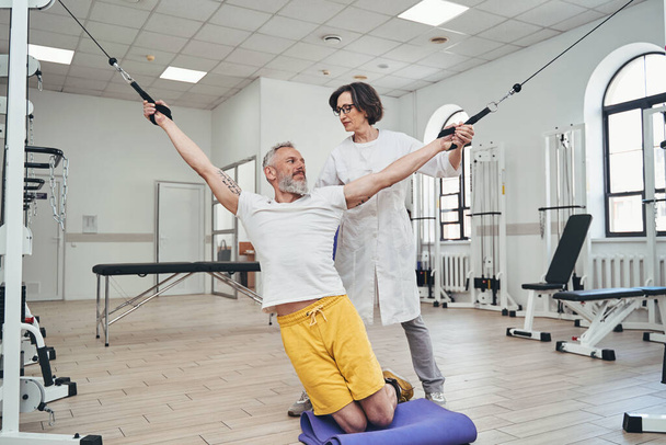 Sportivo che esegue un esercizio di stretching utilizzando una macchina via cavo - Foto, immagini
