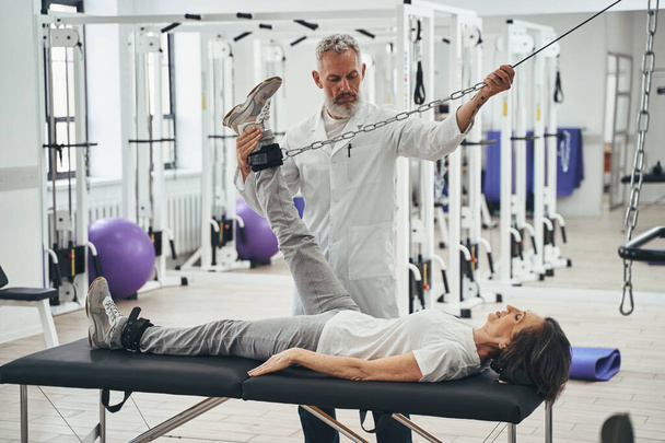 Patient doing a strength training exercise using a cable machine - Photo, Image