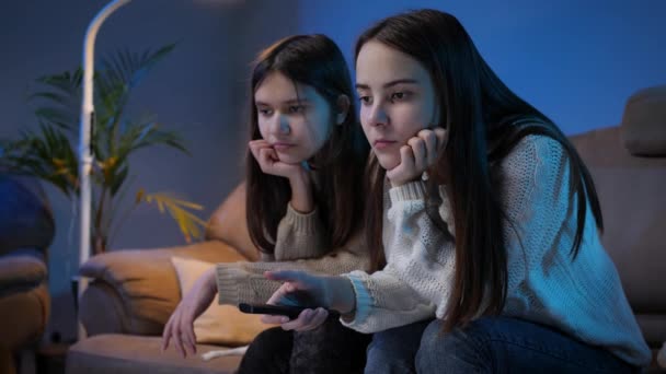 Portrait of young friends getting bored while searching TV show and using remote control - Footage, Video