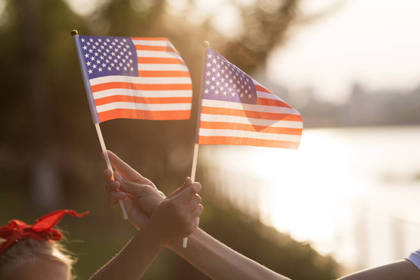 Patriotic holiday. Happy family, mother and daughter with American flag outdoors on sunset. USA celebrate independence day 4th of July. - Foto, afbeelding