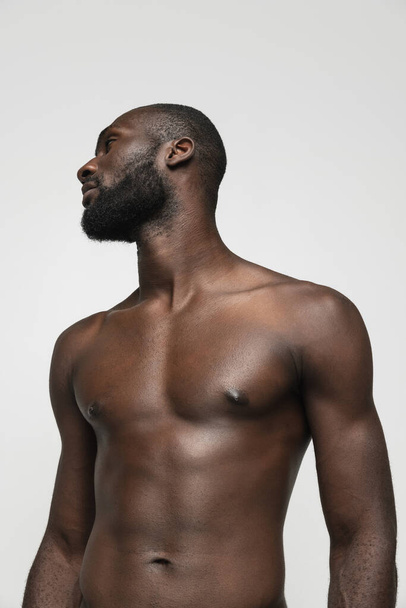Joven hombre africano guapo musculoso posando aislado sobre fondo blanco. Concepto de belleza, cosméticos, spa. - Foto, Imagen