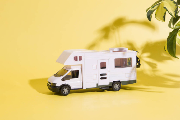 toy travel van on yellow background with plants shadow. Minimalistic summer family travel concept - Photo, Image