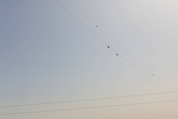 Jebel Jais Flight, nejdelší zipline na světě, lidé v postrojích klouzajících po zip lince proti modré obloze, pohled zdola. - Fotografie, Obrázek