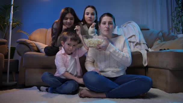 Gran familia viendo programas de televisión nocturnos y comiendo palomitas de maíz en la sala de estar - Imágenes, Vídeo