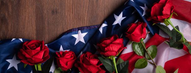 Concept of U.S. Independence day or Memorial day. National flag and red rose over dark wooden table background. - Фото, изображение