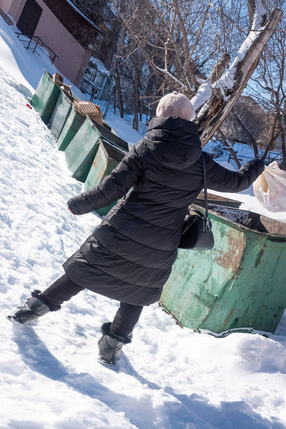 Femme jette les ordures dans les poubelles dans la rue en hiver. - Photo, image