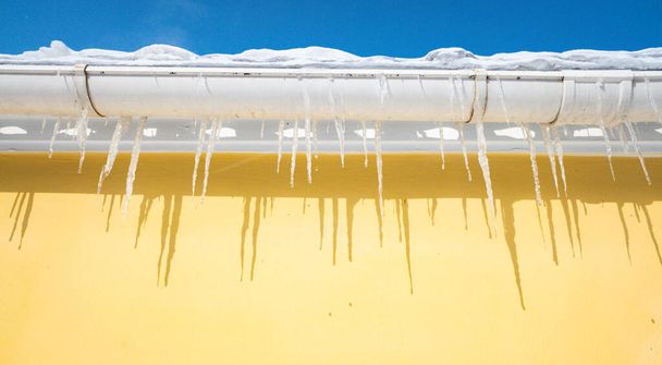 Eiszapfen hängen am Dach des Hauses blauer Himmel - Foto, Bild