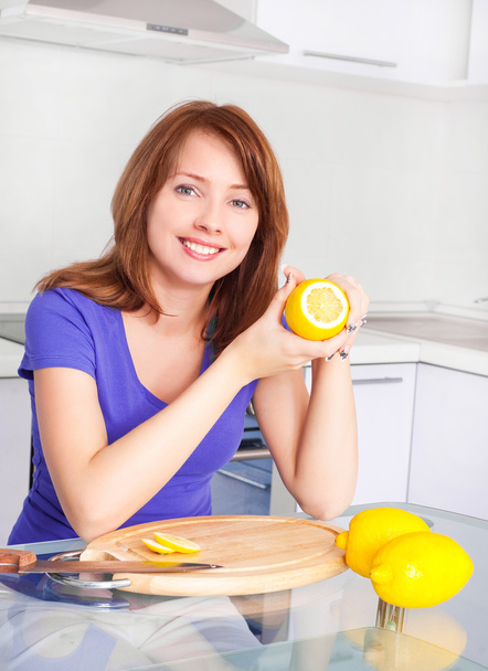 Pretty young woman with lemons in the kitchen at home - Foto, afbeelding