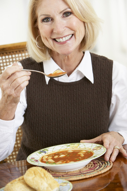 Vanhempi nainen juomassa keittoa
 - Valokuva, kuva