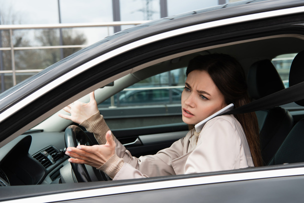 grave jeune femme gestuelle tout en parlant sur smartphone dans la voiture - Photo, image