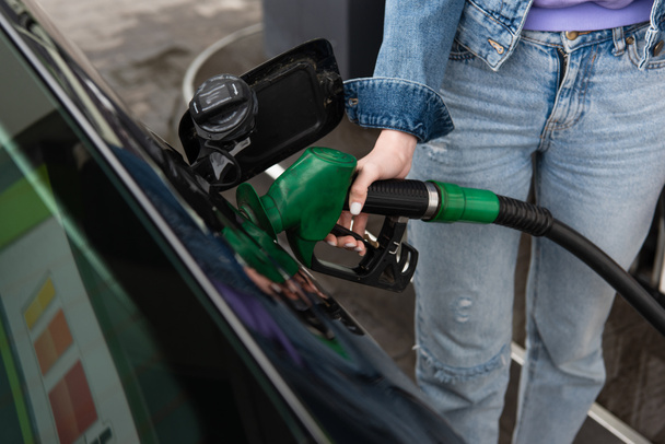 cropped view of woman in jeans fueling car on gas station - Photo, Image