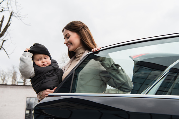 pleased mother standing with little boy near car outdoors - Fotografie, Obrázek