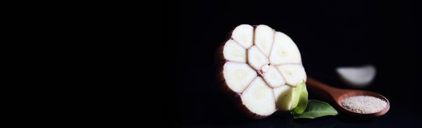 Fresh garlic clove on black background. Garlic is rich in vitamins, useful spring, good spices. Garlic sliced on a dark background. Raw sliced garlic. - Photo, Image
