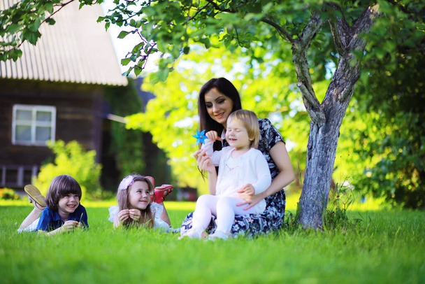 Młoda duża rodzina na letnim porannym spacerze. Piękna matka z dziećmi bawiącymi się w parku. - Zdjęcie, obraz