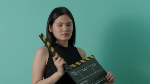 Film tahtası ve küçük seksi Asyalı kız. Kadın, film alkışlama tahtası ya da yeşil ekran arka planlı film tahtası. Gülümsemesini göstermek için kameralar yakınlaşıyor ve uzaklaşıyor. video üretimi. - Video, Çekim