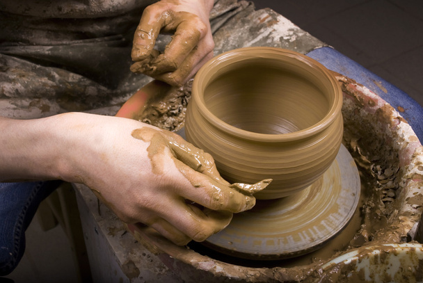 de handen van een pottenbakker, maken een aarden pot op de cirkel - Foto, afbeelding