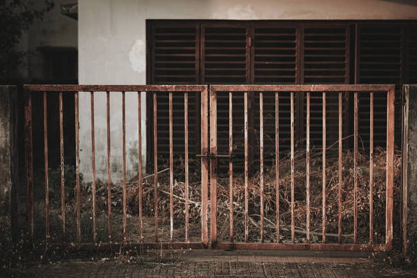 A closeup shot of an abandoned rusty metal gate and building - Foto, immagini