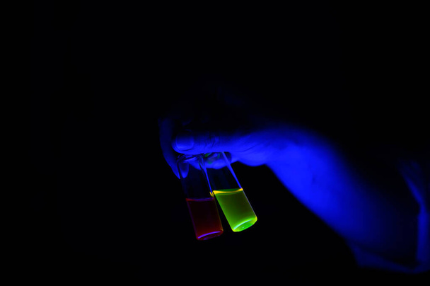 Chemik kobieta naukowiec trzyma parę fluorescencyjny mieszanka roztwór w małej szklanej fiolce dla biotechnolgy badań - Zdjęcie, obraz